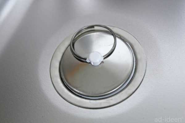 Detailaufnahme eines Edelstahlwaschbeckens mit einem weißen Abflussdeckel, ideal für mobile Wasserversorgungslösungen beim Camping oder Marktständen. Perfekt für den Einbau in Bullis oder Transportern und geeignet für den Einsatz mit Frisch- und Grauwasserkanistern.