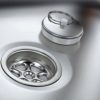 Detailaufnahme eines Edelstahlwaschbeckens mit Abfluss und Deckel, ideal für mobile Wasserversorgung beim Camping oder in Marktständen. Perfekt für den Ausbau von Bullis und Transportern, um frisches Wasser bereitzustellen.
