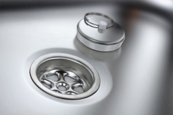 Detailaufnahme eines Edelstahlwaschbeckens mit Abfluss und Deckel, ideal für mobile Wasserversorgung im Campingbereich oder für den Ausbau von Bullis und Transportern. Perfekt geeignet für Frisch- und Grauwasseranwendungen.