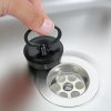 Hand, die einen Deckel für den Abfluss eines Edelstahlwaschbeckens anhebt, ideal für mobile Wasserversorgungslösungen beim Camping oder für Marktstände.